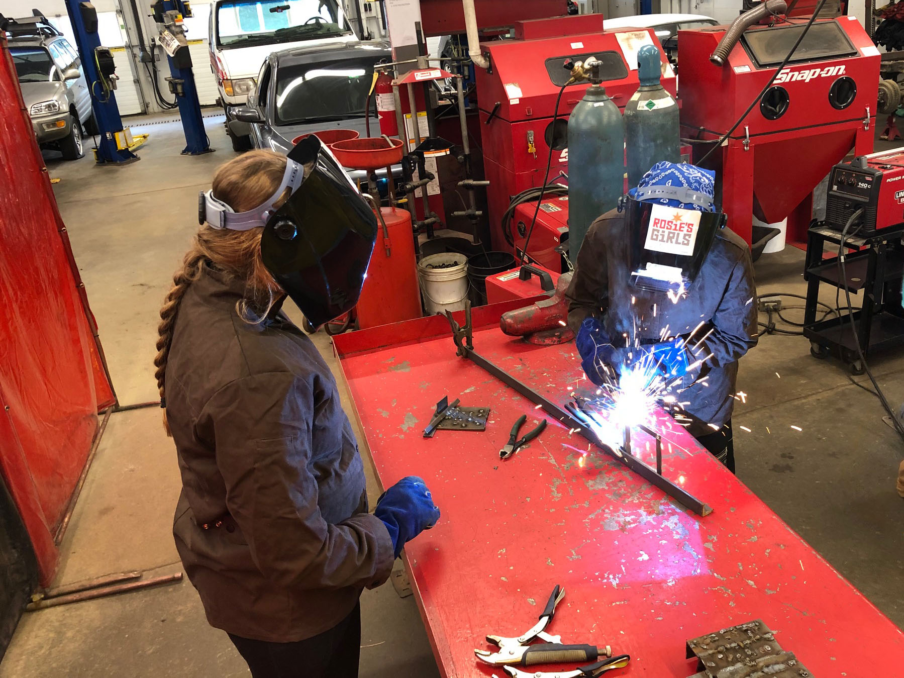 A Rosie’s Girls camper welds a metal rod whilea VWW staff member looks on.