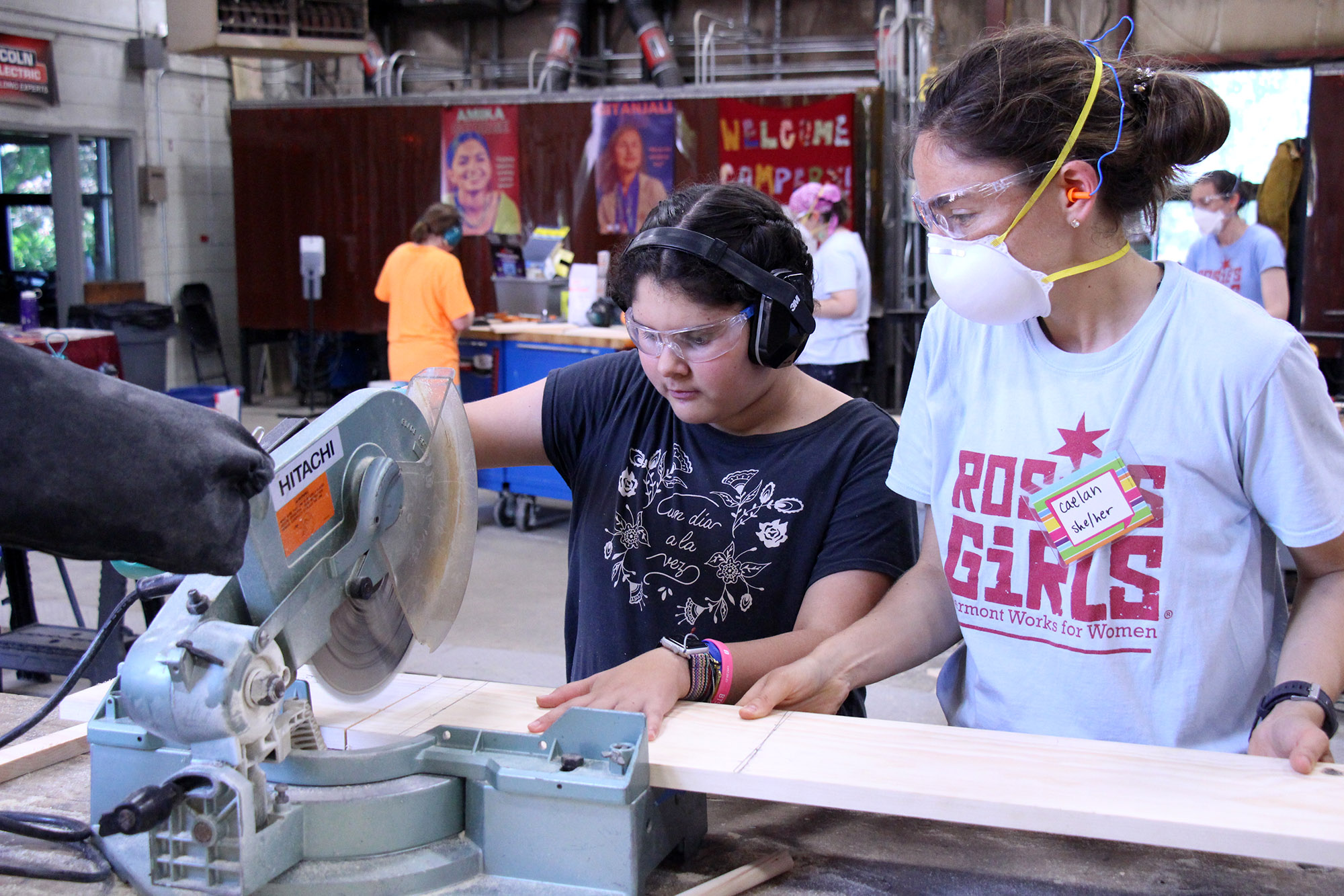 VWW staff member helps camper cut wood using a table saw at Rosie's Girls camp.