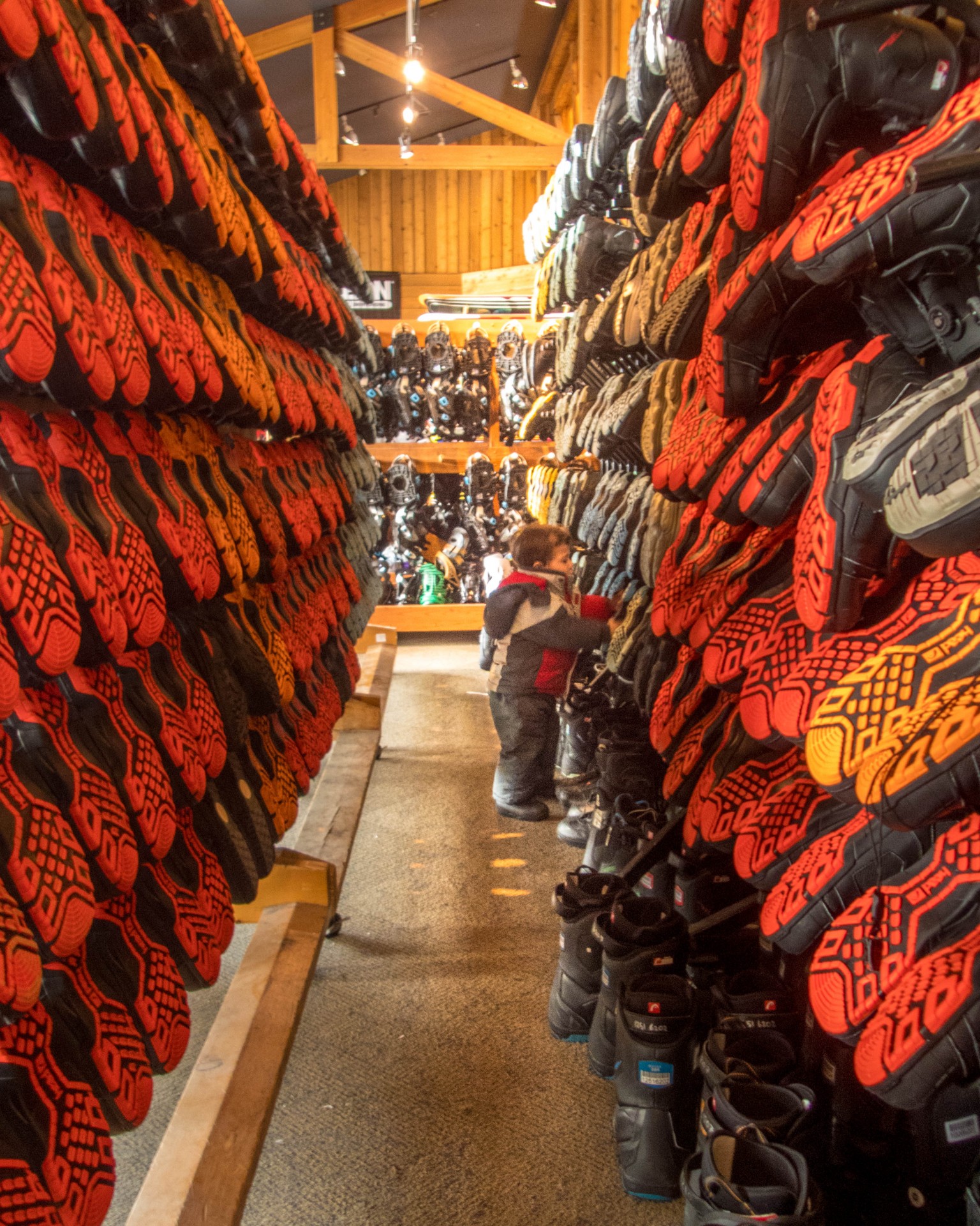 Young boy looks through racks of ski boots - Learning to Ski at Kelowna's Big White