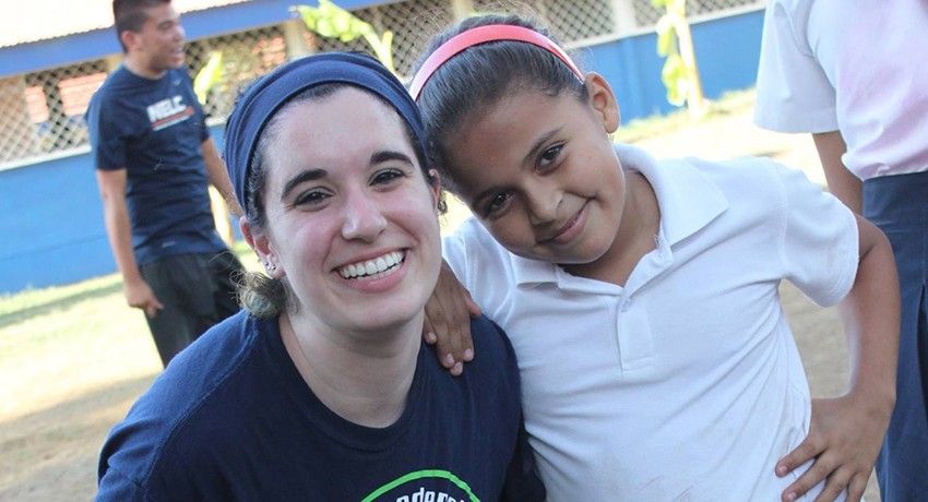 A Worcester state student smiling next to a small child