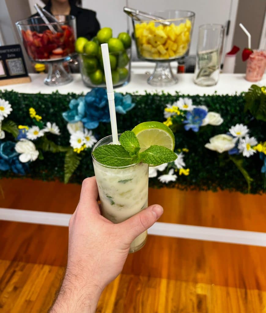 beautiful cocktail with a lime, table in the background, limes, lemons, strawberries on display, SINTONIA BARTENDERS, Orlando, FL