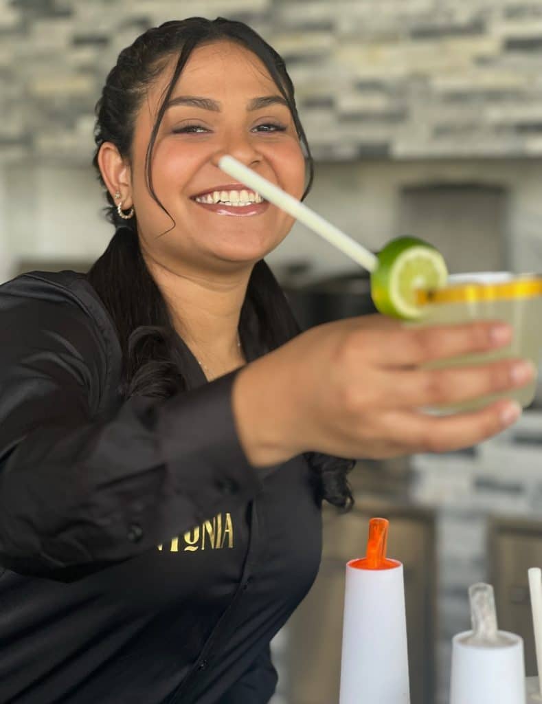 bartender holding out a drink she made with a lime garnish, Orlando, FL