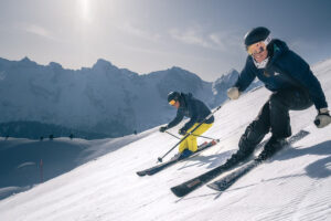 two skiers racing down the piste, smiling big