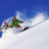 two skiers off-piste, against a bright blue sky