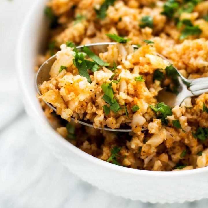 Close up photo of a spoonful of Spanish Cauliflower Rice resting in a bowl of keto rice.