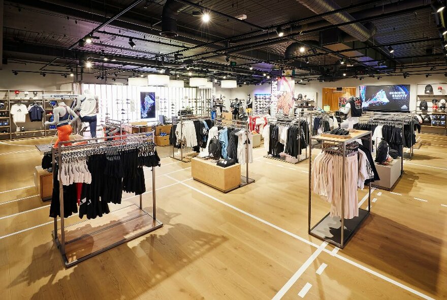 Interior of a large Adidas store with many racks of sports clothing