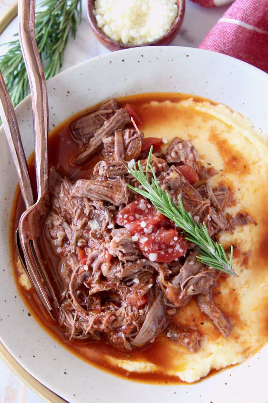 Shredded beef ragu sauce served over creamy polenta in bowl