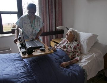 A nurse's aide helps nursing home patient Louise Irving on Wednesday, March 25, 2015. (Richard Drew/AP Photo)