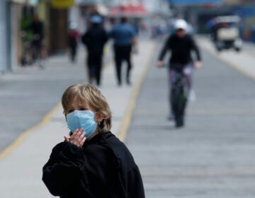 A boy adjusts his mask as he walks down the boardwalk, Thursday, May 21, 2020 in Wildwood, N.J. (AP Photo/Matt Slocum)