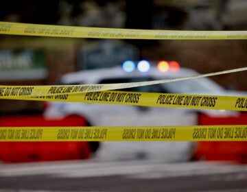 Police tape and the flashing lights of a police vehicle behind