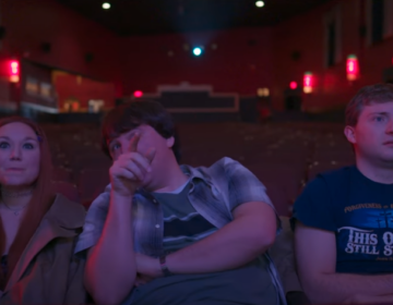 Three people sit in a theater