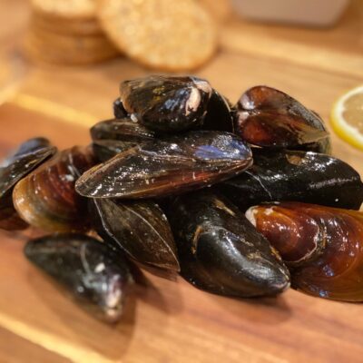 A pile of fresh mussels on a wooden board.