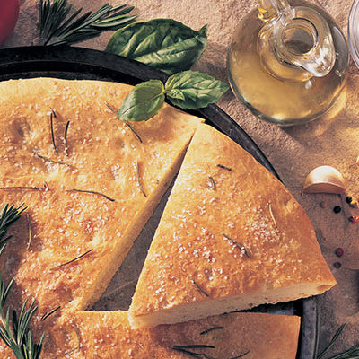 Focaccia on a table with tomatoes on the side