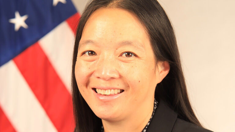 Karen Hyun poses for a portrait with a U.S. flag in the background.