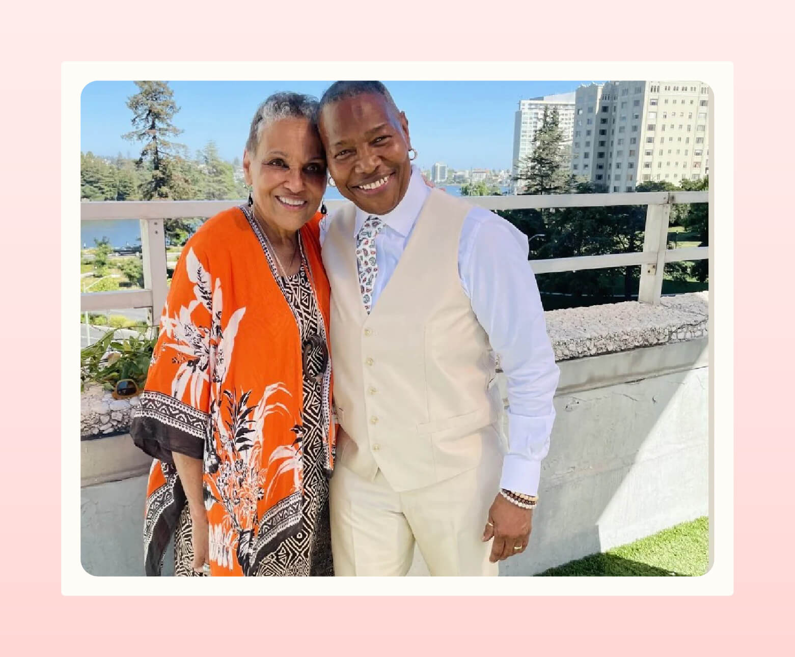 Two women pose for photo, one wearing a cream vest and pants from Hautebutch and the other wearing an orange and black dress