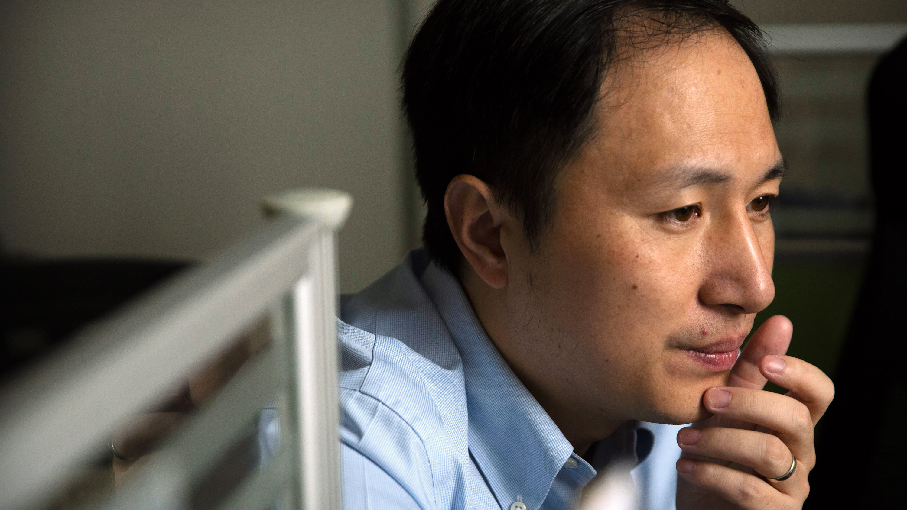 He Jiankui in profile looking to a computer screen out of frame