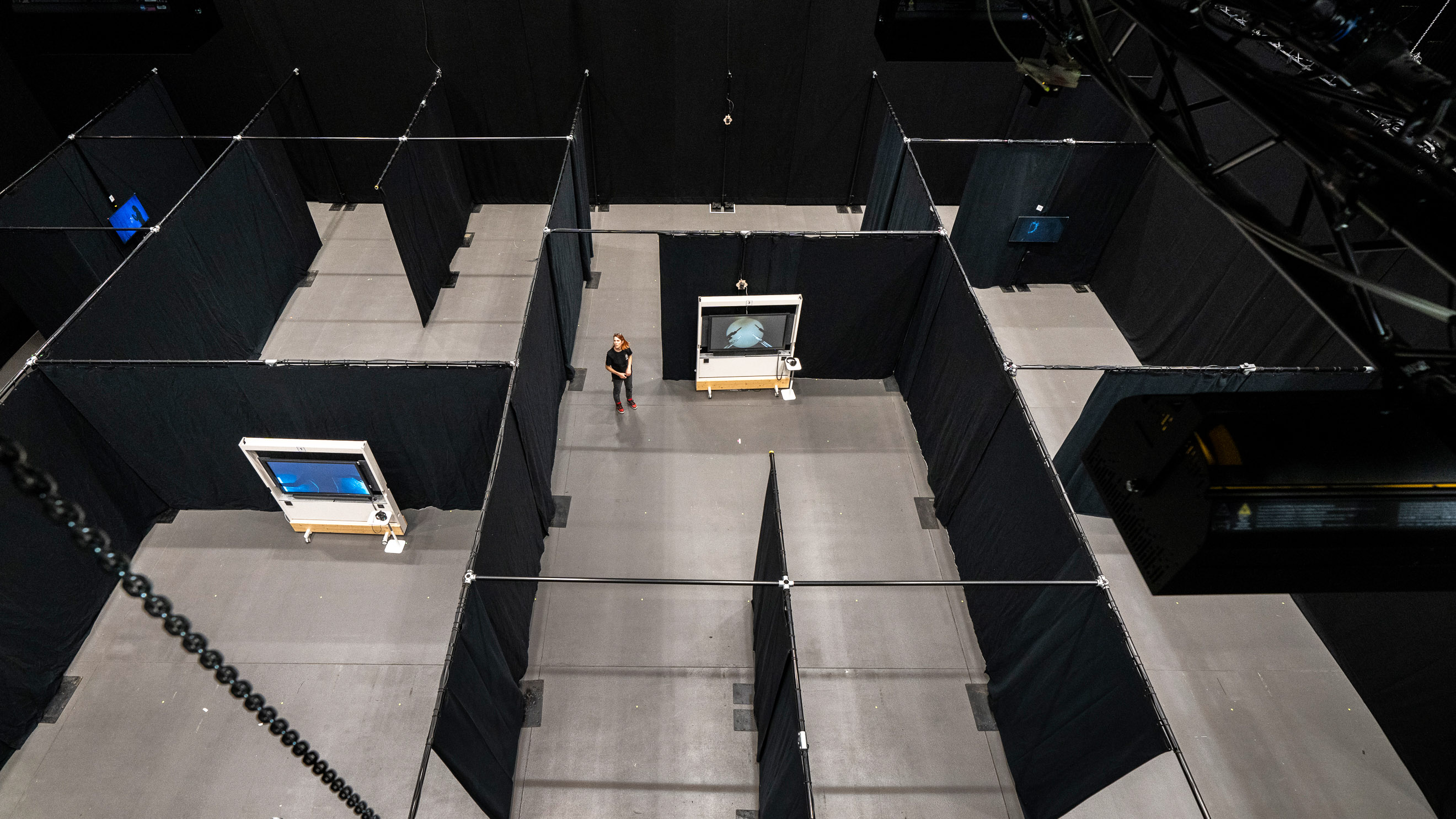 overhead view of a pipe and drape sectioned room of a convention center with a person standing at the center near a display