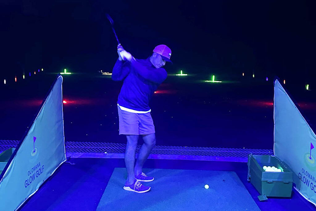 golfer at driving range hitting glowing golf ball