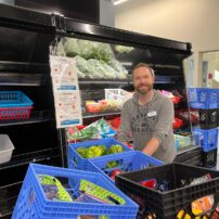 Volunteer Alex stocks the vegetable cooler.