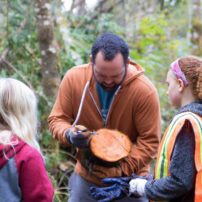 Great Peninsula Conservancy Executive Director Nate Daniel explaining tree rings with Land Labs students