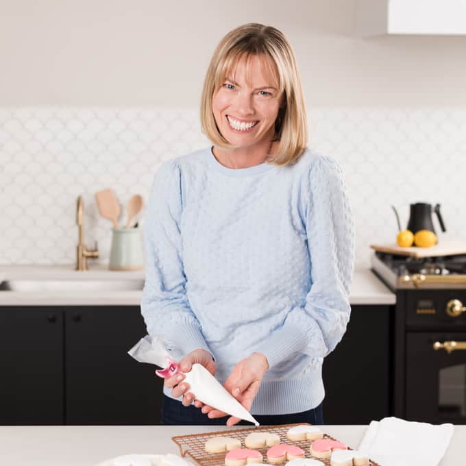 Holly Baker square photo in blue sweater icing cookies in kitchen