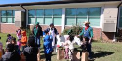 A group of children listening to adults talk about dairy cows at the Farmers Walk event.