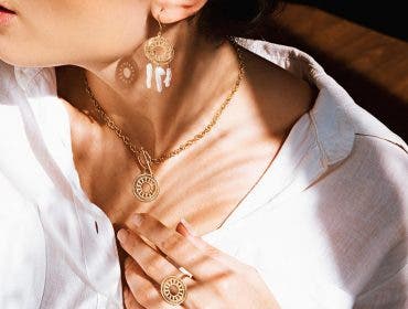 woman modeling gold earrings, necklace, and ring for jewelry photography shoot