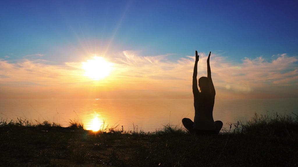 woman meditating at sunset