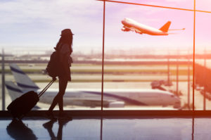 Woman watching airplane take off from airport window