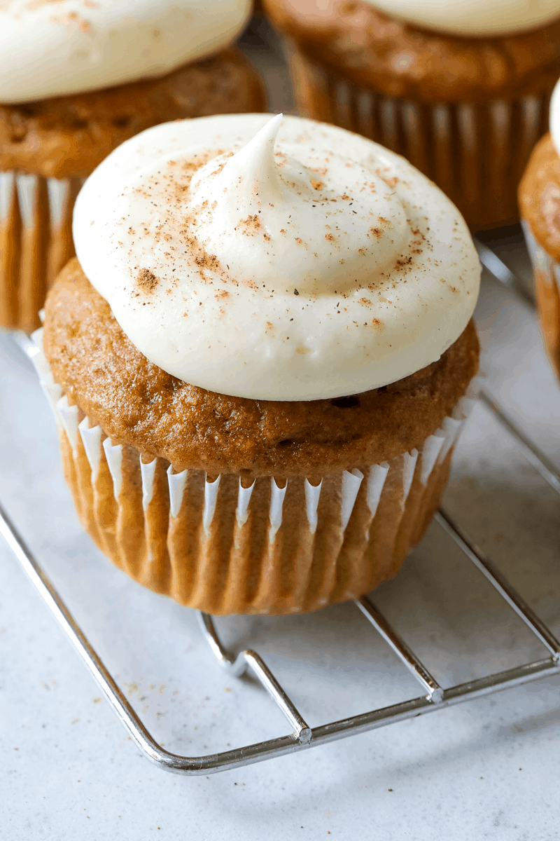 close up of a cupcake with frosting sitting on a wire rack