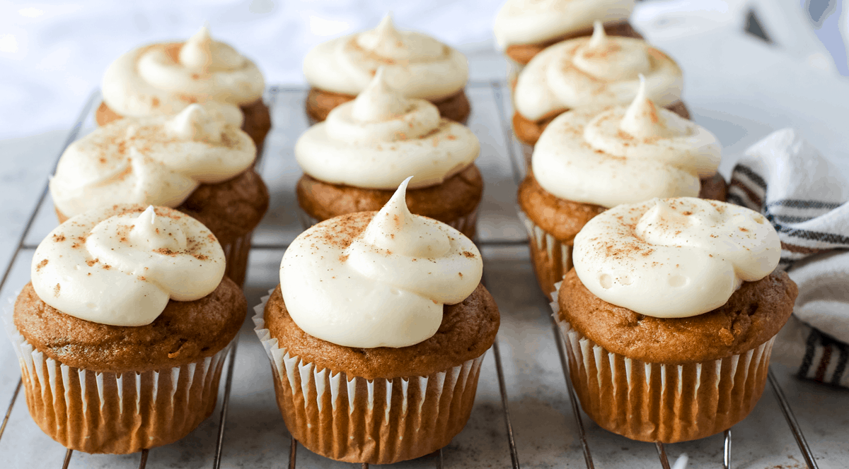 pumpkins with frosting sitting on a wire rack