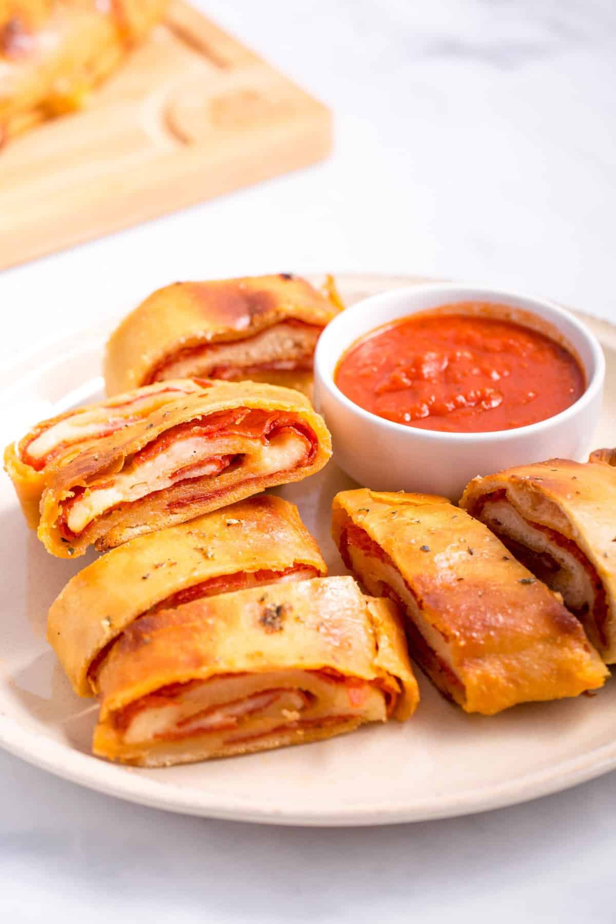 sliced pepperoni bread served on a white plate with a side of pizza sauce