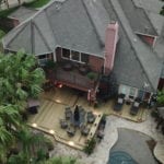 A beautifully designed residential deck made with custom wood, featuring a spacious outdoor seating area, railing, and steps, providing a perfect space for relaxation and entertainment.