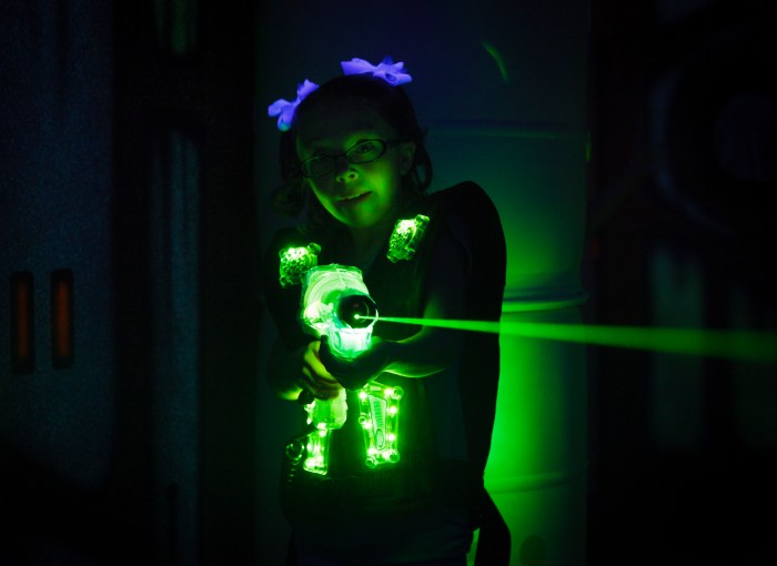 A little girl playing laser tag. Photographed at a high ISO under black light to capture true look and feel of game.