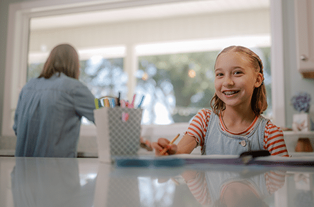 Homeschool student learning math in the kitchen while her mom washes dishes