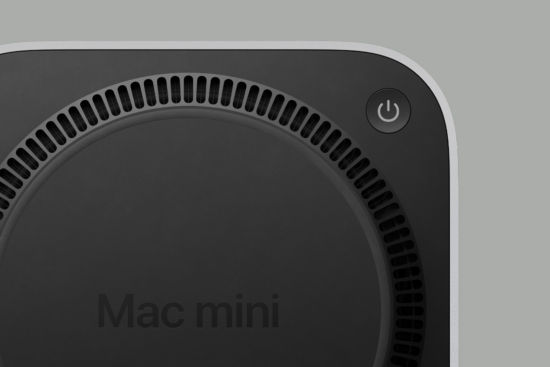 Долната част на Mac mini, черна на цвят, с бутон за захранване и ветрилообразна вентилационна архитектура