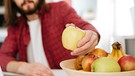 Junger Mann sitzt vor PC und greift zum Obst. Früchte wie Äpfel und Bananen bergen viele Geheimnisse. Wir lüften einige. | Bild: colourbox.com