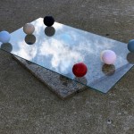 Sculpture formed from a glass pane with several balls balanced atop and below it.