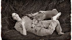 Photographer Sally Mann relaxes with her dog Honey in a meadow of tall grass on her farm near Lexington, Virginia.