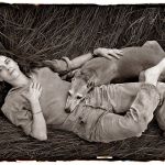 Photographer Sally Mann relaxes with her dog Honey in a meadow of tall grass on her farm near Lexington, Virginia.