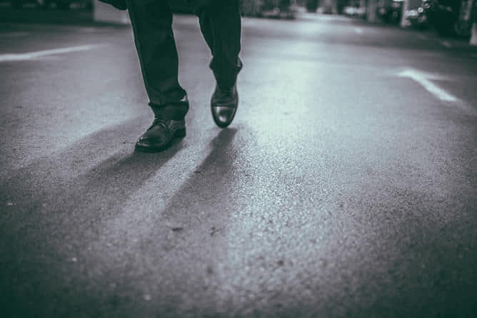 The focus is on someone's feet as they walk through a parking garage.