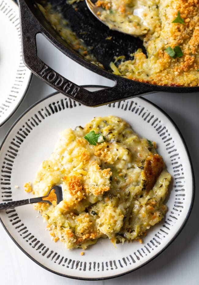 Top down view cheesy zucchini casserole portion on a plate with fork.