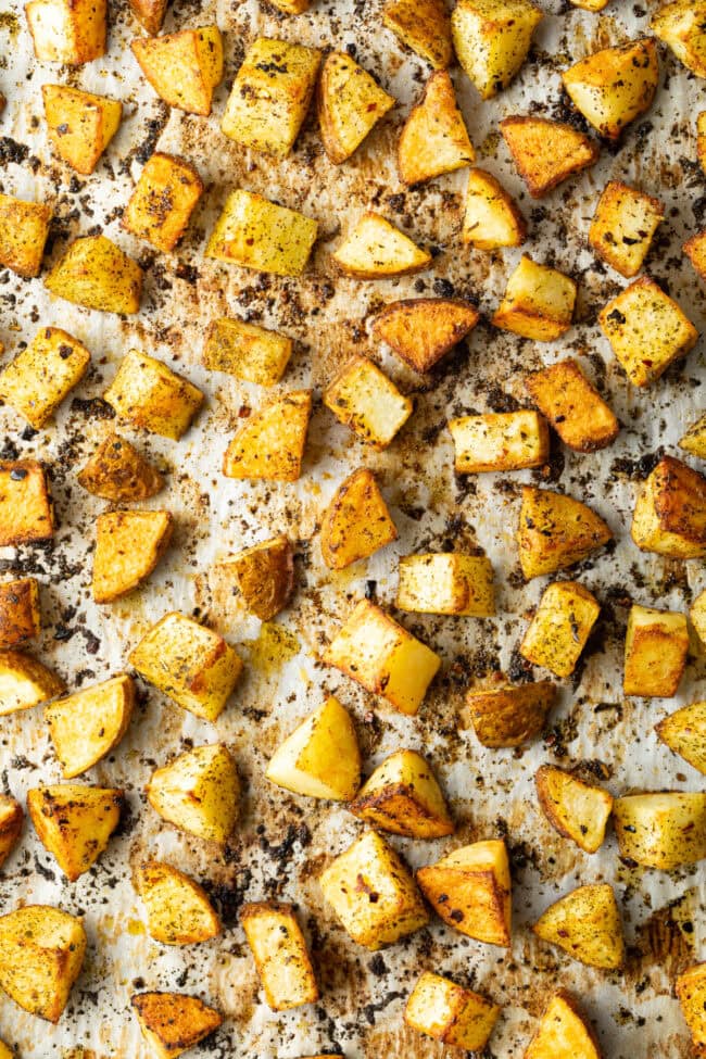 Top down view cubes of roasted russet potatoes on a baking sheet lined with parchment.