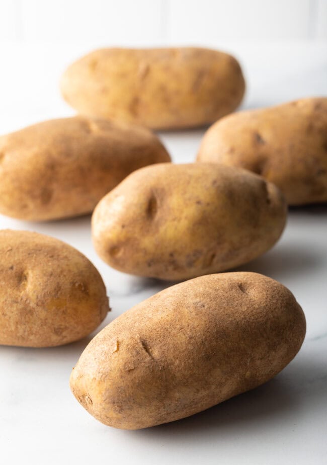 6 russet potatoes on a white background.