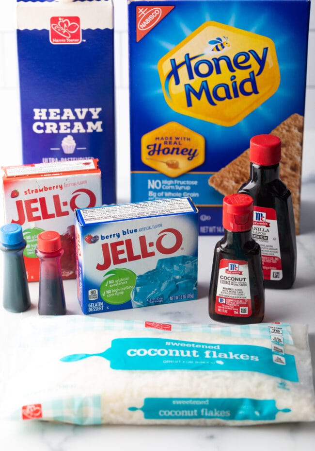 Recipe ingredients: two boxes of red and blue Jello, box of graham crackers, heavy cream, red and blue food coloring, bag of coconut flakes, and two bottles of extract.