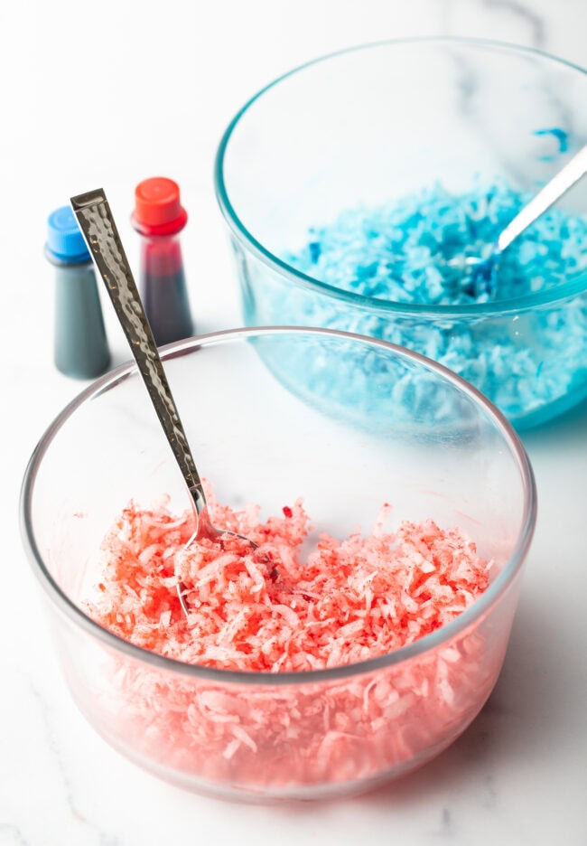 Adding red food coloring to glass bowl with shredded coconut.