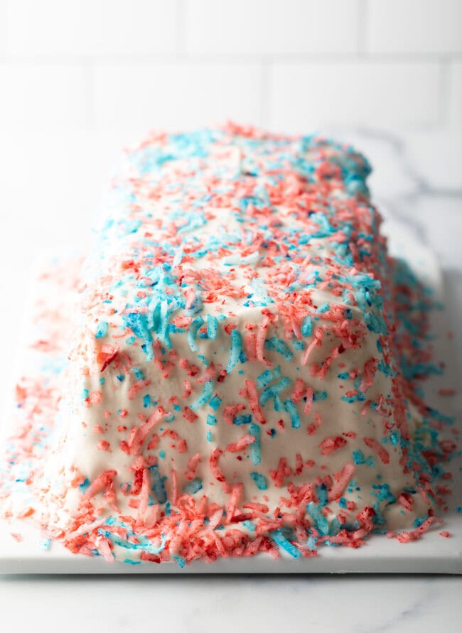 White rectangular icebox cake covered with red and blue coconut flakes.