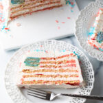 Top down view of a slice of American flag cake on a white plate, with fork.