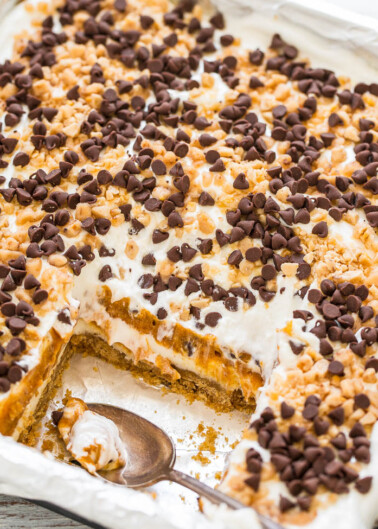 A pan of baked dessert with a portion scooped out, topped with marshmallows and chocolate chips.