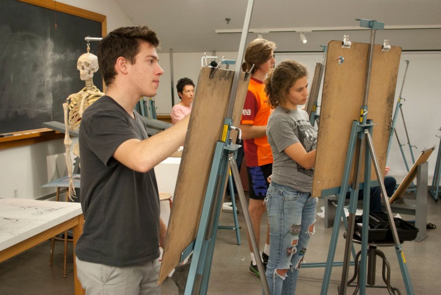 Students at Bates College draw at easels at a life drawing session 